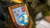 Das Verbandsabzeichen der Marineschifffahrtleitung als Patch auf der Schulter eines Soldaten in Flecktarnuniform.