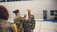 Der Corona-Test Eine Soldatin führt mit einem Soldaten einen Covid-19-Test in einer Halle durch
