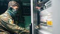 Ein Soldat sitzt in einem Container und betreibt die Datenverbindung von Kreta nach Husum.