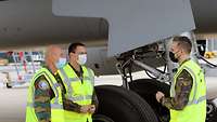 Soldaten stehen vor einem Flugzeugfahrwerk.