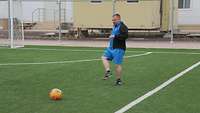 Ein Soldat kickt gegen einen Fußball