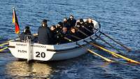 Mehrere Soldaten sitzen in einem Boot und rudern.