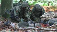 Zwei Soldaten versorgen eine dritte verletzte Soldatin.