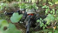 Zwei Soldaten liegen getarnt in einem Gelände.