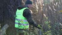 Ein Soldat im Feldanzug steht im Dickicht und blickt sich um.