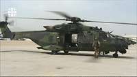 Soldat steht vor einem Hubschrauber vom Typ NH-90