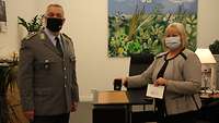 Ein Soldat steht neben einer Frau bei der Verleihung einer Anerkennungsmedaille. 