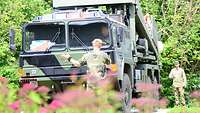 Zwei Soldaten weisen einen weiteren Soldaten mit seinem LKW ein.