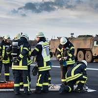 Mehrere Feuerwehrmänner im Einsatz. Im Hintergrund steht ein Feuerwehrauto