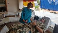 Ein Soldat liegt auf einer Liege und die Krankenschwester steht daneben