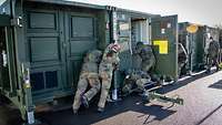 Container werden entkoppelt Mehrere Soldatinnen und Soldaten schieben einen Container