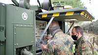 Soldaten schließen Kabel an eine Satelliten-Antenne an.