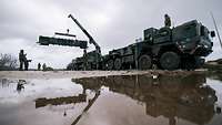 Mehrere Soldaten beladen einen Patriot-Launcher. Dabei hängt ein Kanister mit dem Lenkflugkörper am Ladekran