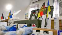 Ein Tisch, auf dem viele medizinische Güter und eine deutsche sowie eine ukrainische Flagge stehen