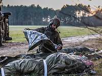 Die Erstversorgung Ein Soldat deckt einen Verletzten mit einer Rettungsdecke zu.