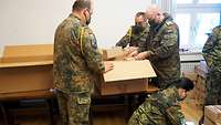Mehrere Soldaten packen Weihnachtspakete in einem geschlossenem Raum.