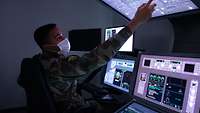 Ein französischer Soldat sitzt am Simulator und bedient Touchscreen-Monitore.