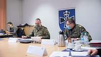 Zwei Soldaten sitzen nebeneinander an Tischen