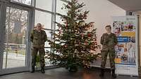 Zwei Soldaten stehen frontal zur Kamera, zwischen ihnen steht der Weihnachtsbaum