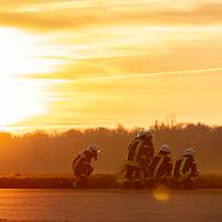 Feuerwehrleute trainieren im Sonnenuntergang auf dem Flugplatz in Jever.