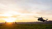 Ein Hubschrauber startet im Sonnenuntergang.