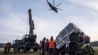 Ein Übersichtsbild nach dem Sprengstoffanschlag auf zwei Fahrzeuge. Über der Unfallstelle fliegt ein Hubschrauber.