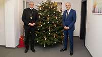 Militärbischof Bernhard Felmberg und Staatssekretär Gerd Hoofe stehen vor einem Weihnachtsbaum