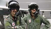 Zwei Eurofighterpiloten stehen nebeneinander und tragen Helme und Oberlippenbart.