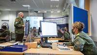 Mehrere Soldatinnen und Soldaten beraten sich über Details des Wargame