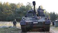 Eine Panzerhaubitze von vorn, darauf ein Soldat, daneben steht ein weiterer Soldat