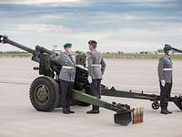 Die Geschützbesatzung Drei Soldaten in Heeresuniform stehen in Position an einer Feldhaubitze.