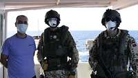 Zwei Boardingsoldaten und der Kapitän des Schiffes blicken für ein Erinnerungsfoto in die Kamera 