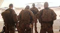 Mehrere Soldaten mit Ausrüstung, im Hintergrund ein Hubschrauber 