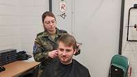 Soldatin schneidet auf der Ämari Airbase einem Soldaten die Haare.