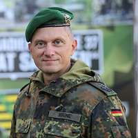 Ein Soldat steht vor einem Banner mit einem sächsischen Wappen.