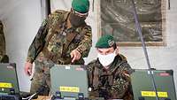 Soldaten in grüner Uniform arbeiten an einem Computer in Unterrichtssaal.