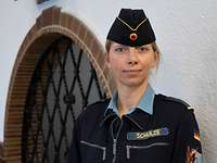 Eine Frau mit Marinemütze vor einer Wand.