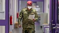 Ein Soldat mit einem Blatt Papier in der Hand, geht einen langen Flur entlang.