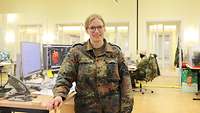 Eine Frau in Uniform steht an einem Schreibtisch