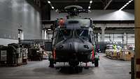 Ein Militärhubschrauber ohne Rotorblätter steht in einer Lagerhalle.