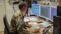 Ein Soldat sitzt an seinem Arbeitsplatz und erstellt eine Karte am Computer