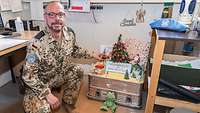 Ein Soldat kniet in seinem Büro neben einem weihnachtlich gedeckten Tisch