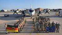 Viele Menschen in Uniform stehen in Form der Zahl zwölf vor einem großen grauen Flugzeug