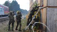Mit dem Gewehr im Anschlag dringt ein Soldat über eine Leiter in ein Haus ein. Gesichert wird er von zwei Kameraden.