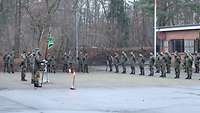 Auf einer Betonfläche stehen Soldaten in Formation.