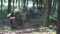 Mehrere Soldaten bewegen sich gut getarnt durch den Wald.