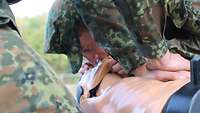 Ein Soldat übt an einer Trainingspuppe die Beatmung eines Bewusstlosen.