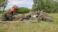 Soldaten liegen auf einer Wiese bewaffnet nebeneinander. Die Schießplätze sind nummeriert.