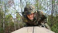 Ein Soldaten bewegt sich über zwei verbundene flache Holzbalken.