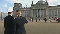 Ein Soldat und eine Soldatin, von hinten gesehen, stehen vor dem Reichstagsgebäude
